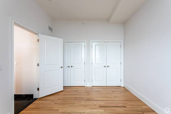 Three white doors in a room with wooden floors.