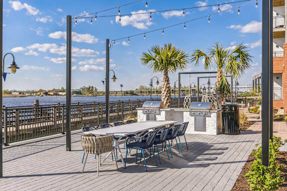 a patio with a table and chairs and a bar and a body of water at Metropolitan at the Riverwalk, North Carolina