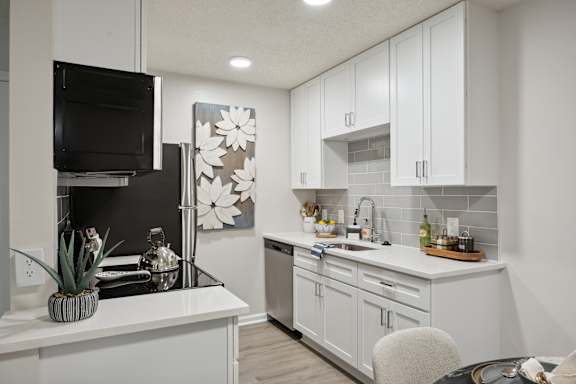 A modern kitchen with white cabinets and a black fridge at St. Andrews Reserve Apartments in Wilmington, NC