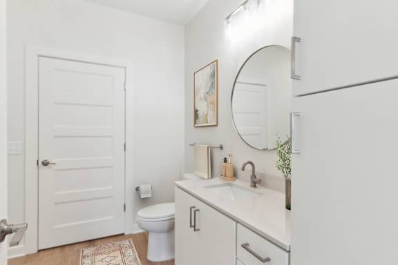 A white bathroom with a toilet, sink, and mirror at Hawkins Press, Charlotte, North Carolina