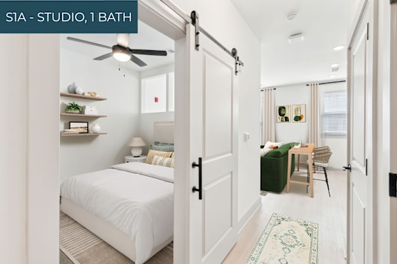 A bedroom with a bed, a chair, and a ceiling fan.