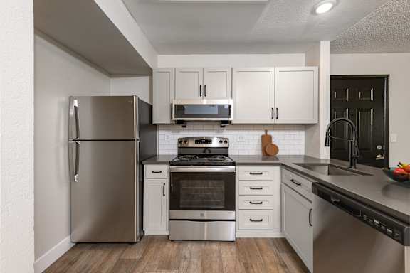 A modern kitchen with stainless steel appliances and white cabinets.