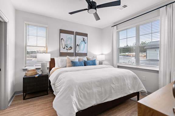 A bedroom with a large bed and a ceiling fan.
