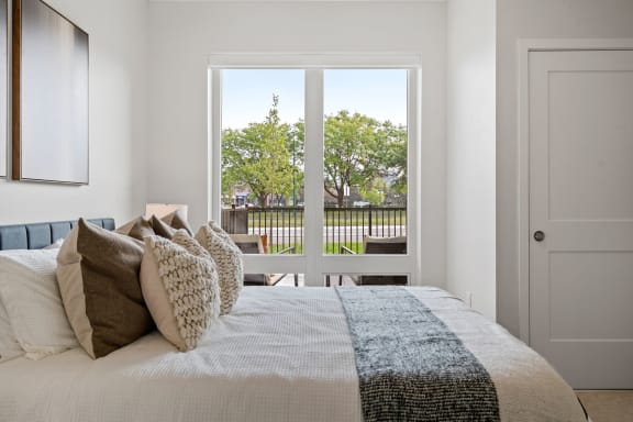 a bedroom with a large window and a bed with pillows