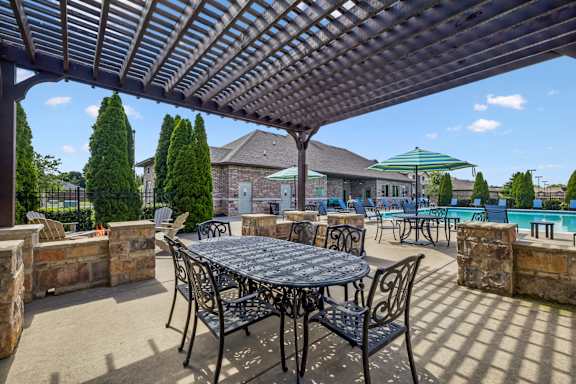A patio with a table and chairs under a pergola.