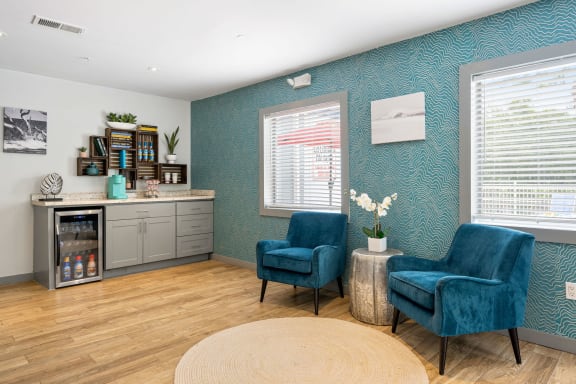 a therapy room with two blue chairs and a counter with a drinks station