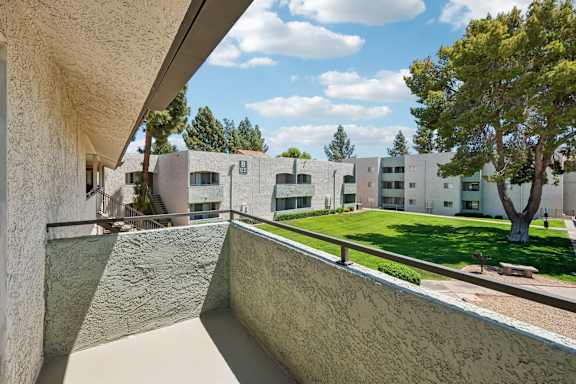 A view from a balcony looking out at a courtyard with a tree.