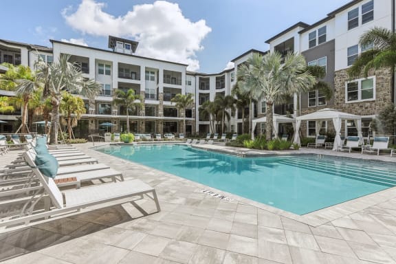 a swimming pool with lounge chairs and a building in the background