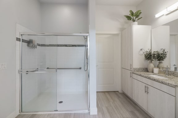 a white bathroom with a glass shower and white cabinets