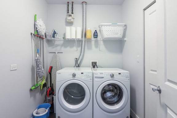 a white washer and dryer in a laundry room with a shelf above it