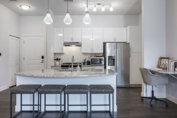 a kitchen with a large island with three stools in front of it