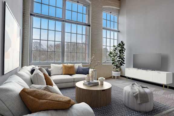 a living room with a couch and a tv in front of large windows