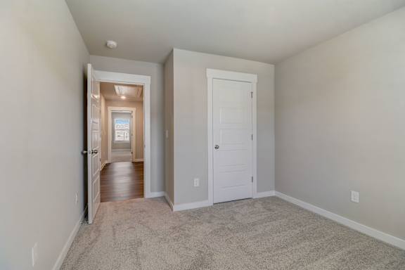 A hallway with a carpeted floor and white walls.