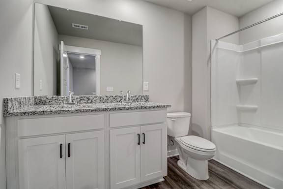 A white bathroom with a marble counter top and a white tub.