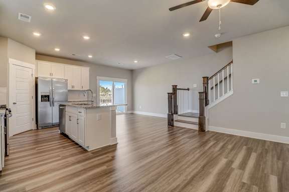 A spacious kitchen with a refrigerator, cabinets, and a ceiling fan.