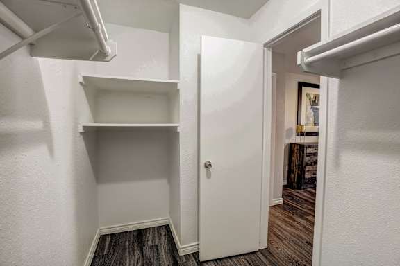 A white door is open to a room with a wooden floor.