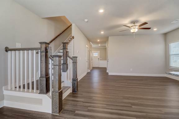 A spacious room with a staircase and a ceiling fan.