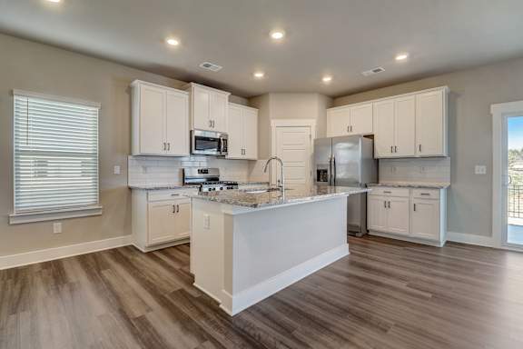 A kitchen with white cabinets and a wooden floor.