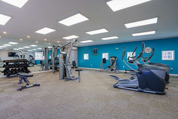 A gym with a variety of equipment including treadmills, weights, and exercise machines.