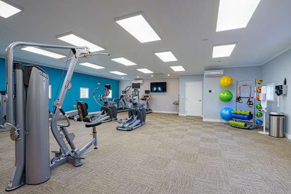 A gym with a variety of equipment and a TV on the wall.