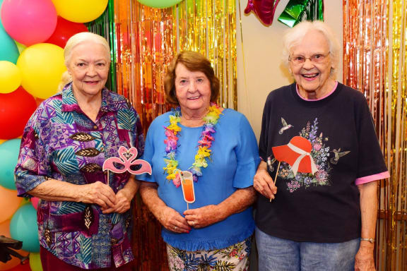 three women standing in front of balloons at a party at River Commons Senior Living, Redding, CA 96002