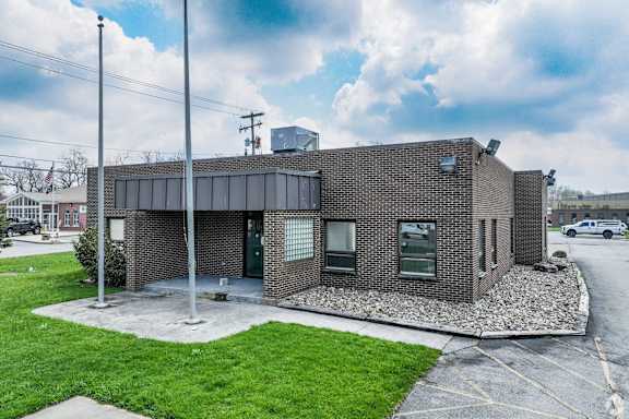 a small brick building with a lawn in front of it
