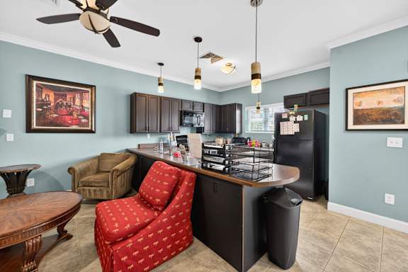 A kitchen with a red chair and a ceiling fan.
