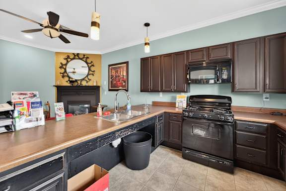 A kitchen with a black stove and a clock on the wall.