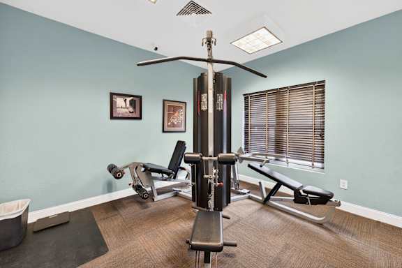 A gym room with a rowing machine and a bench.