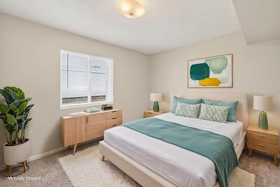 A bedroom with a bed, nightstands, and a plant.
