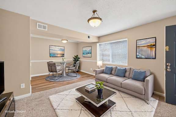 A living room with a grey couch, a coffee table, and a painting on the wall.