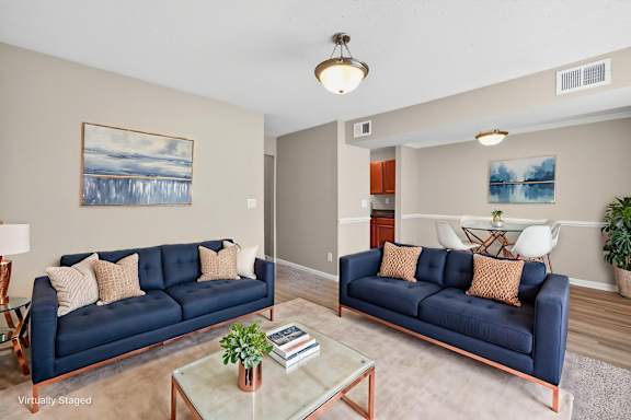 A living room with a blue couch and a painting on the wall.