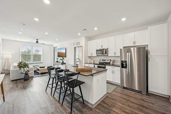 an open kitchen and living room with a stainless steel refrigerator at The Quarry Luxury Apartment Homes, Fort Collins, 80526