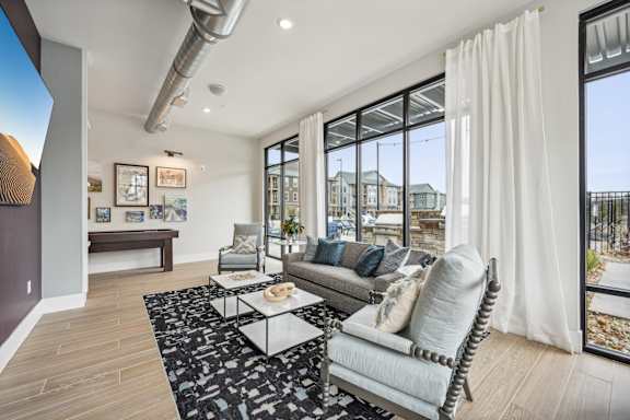 a living room with a couch and a table    and a large window at The Quarry Luxury Apartment Homes, Fort Collins, 80526