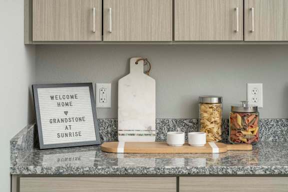 a kitchen counter with a sign that reads welcome home and gratitude at sunset at Grandstone at Sunrise, Peoria, AZ, 85383