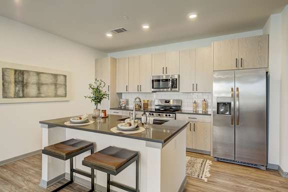 a kitchen with stainless steel appliances and a island with three stools