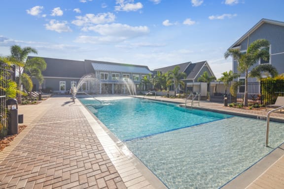 a swimming pool with a fountain in front of a house  at Palm Grove, Florida