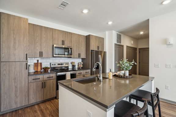 a kitchen with a large island with a counter top and a sink at Stella Luxury Apartment Homes, San Tan Valley, AZ, 85143
