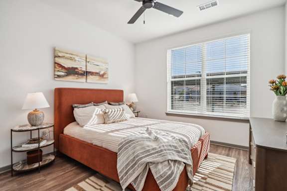 A bedroom with a bed, a ceiling fan, and a painting on the wall at The Pullman Luxury Apartment Homes, Atlanta