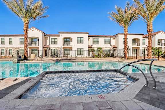 a swimming pool with palm trees and apartments in the background