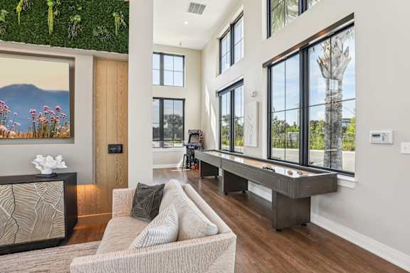 A modern living room with a large window and a view of a tree. at Drift, Daytona Beach, FL, 32117