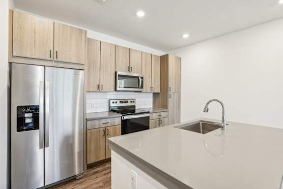 A modern kitchen with a stainless steel refrigerator and wooden cabinets. at Drift, Daytona Beach, FL, 32117
