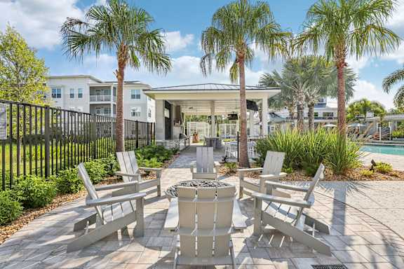 A patio with chairs and a table surrounded by palm trees at Drift, Daytona Beach, FL, 32117