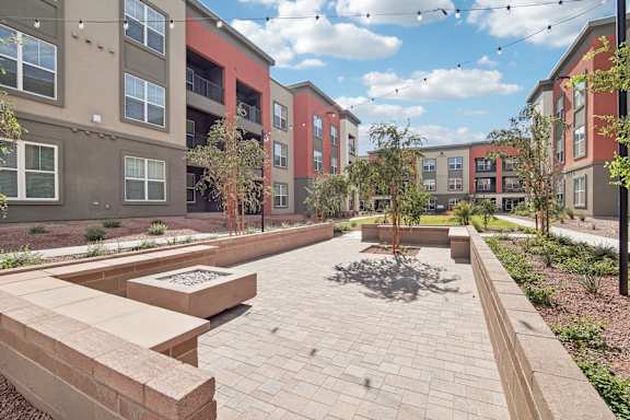an outdoor area with benches and trees in front of an apartment building at The Maddox Luxury Apartment Homes, Arizona, 85326