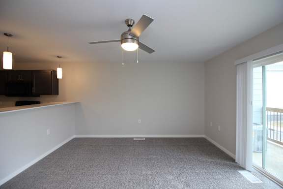 A room with a ceiling fan and carpeted floor.