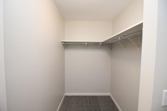 A small, empty room with a carpeted floor and a metal shelf.