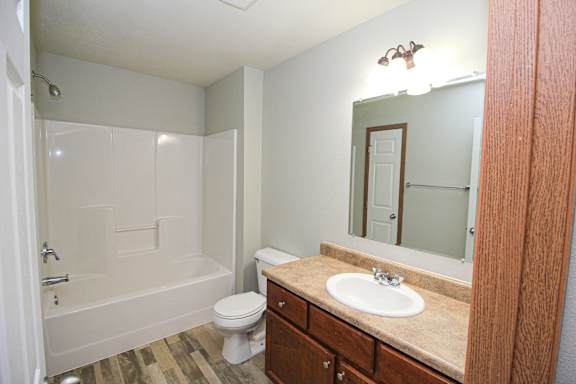 A white toilet sits under a mirror in a bathroom.