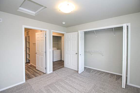 A white closet with a white door and a white laundry basket.