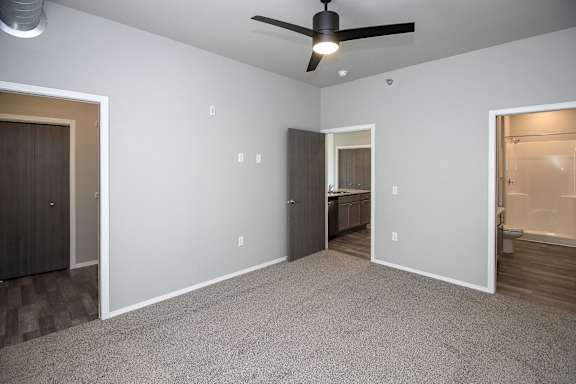 A room with a ceiling fan and carpeted floor.