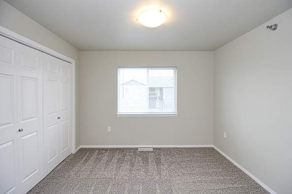 A room with a carpeted floor and a window.